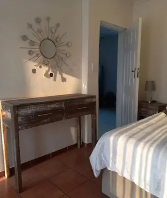 a bedroom with a wooden table with a mirror on the wall at Lime Court One in Pretoria