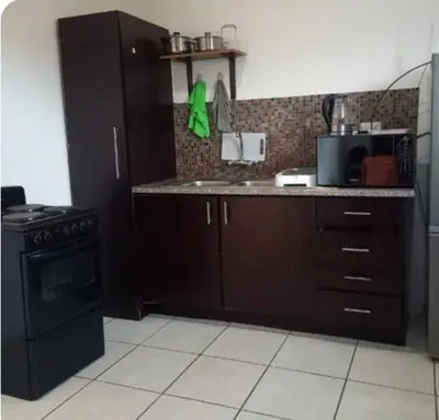 a kitchen with brown cabinets and a black stove at Lime Court One in Pretoria