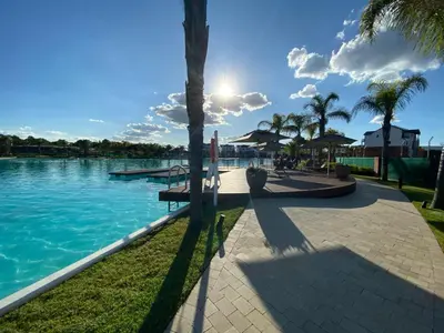a swimming pool with palm trees and the sun at The Blyde Magna Host Luxury Apartments in Pretoria