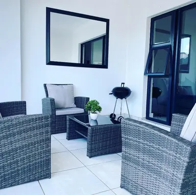 a living room with wicker chairs and a mirror at The Blyde Magna Host Luxury Apartments in Pretoria