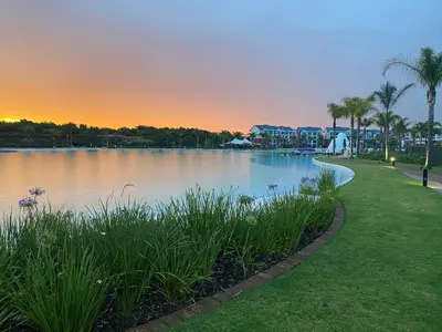 a lake at sunset with palm trees and houses at The Blyde Magna Host Luxury Apartments in Pretoria