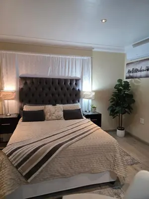 a bedroom with a large bed with a large headboard at Halfway Gardens Home in Midrand