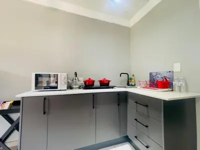 a kitchen with white cabinets and red appliances at ANG COMSAT Guesthouse in Northam