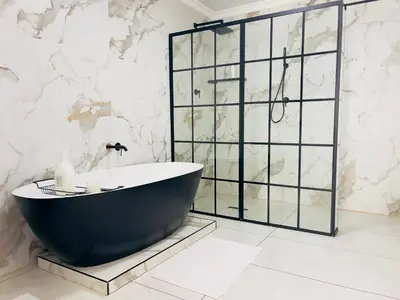 a bath tub in a bathroom with a marble wall at ANG COMSAT Guesthouse in Northam