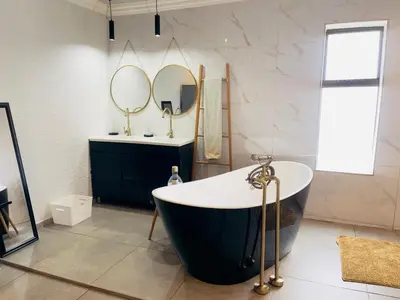 a bathroom with a large tub and two mirrors at ANG COMSAT Guesthouse in Northam