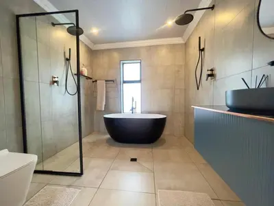 a bathroom with a tub and a glass shower at ANG COMSAT Guesthouse in Northam