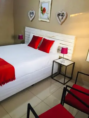 a bedroom with a large white bed with red pillows at Asante’s Guest House in Calcutta