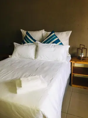 a bed with white sheets and blue and white pillows at Asante’s Guest House in Calcutta