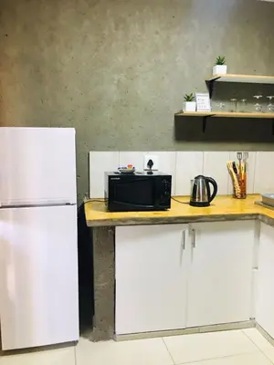 a kitchen with a counter with a microwave and a refrigerator at Asante’s Guest House in Calcutta