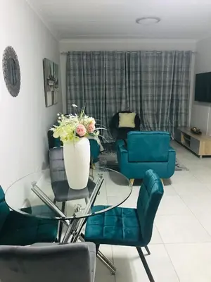 a living room with blue chairs and a glass table at The blyde Pretoria unit 1244 in Pretoria