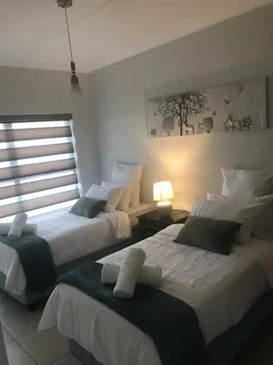 two beds in a room with two lamps and a window at The blyde Pretoria unit 1244 in Pretoria