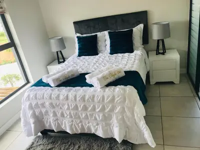 a bedroom with a large white bed with blue pillows at The blyde Pretoria unit 1244 in Pretoria