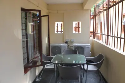 a room with a table and chairs and windows at Lalamnandzi3 in Nelspruit