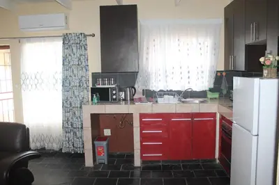 a kitchen with red cabinets and a white refrigerator at Lalamnandzi3 in Nelspruit