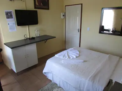 a bedroom with a bed and a desk with a television at Lalamnandzi1 in White River