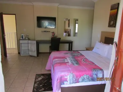 a bedroom with a bed and a desk in a room at Lalamnandzi2 in White River