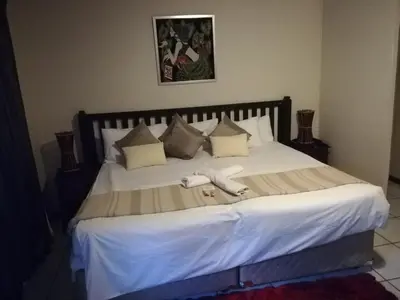 a large bed with white sheets and pillows at Sun Deck Lodge in Hartbeespoort