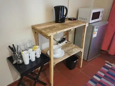 a small wooden table with cups and a microwave at Sun Deck Lodge in Hartbeespoort
