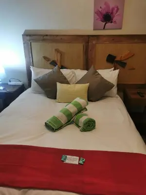 a bed with green and white pillows on it at Sun Deck Lodge in Hartbeespoort