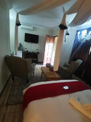 a bedroom with a bed and two chairs and a television at Sun Deck Lodge in Hartbeespoort