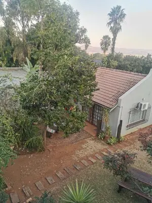 a house with a tree in front of it at Sun Deck Lodge in Hartbeespoort
