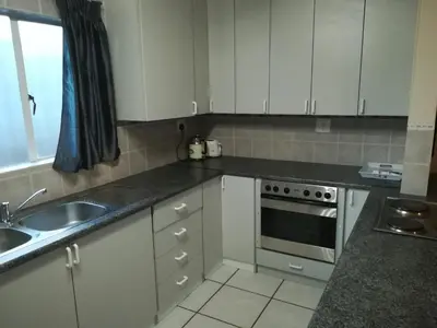 a kitchen with white cabinets and a sink and a stove at Sun Deck Lodge in Hartbeespoort