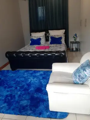 a living room with a couch and a blue rug at Ruros Guest House in Kempton Park