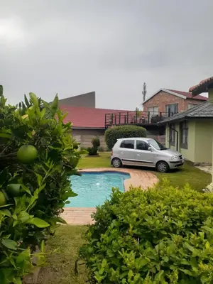 a car parked in front of a house with a pool at Ruros Guest House in Kempton Park