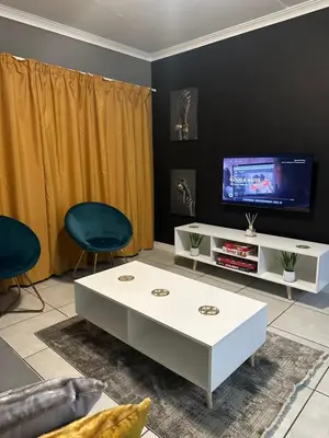 a living room with a white coffee table and a tv at The Blyde Boutique Apartments in Pretoria