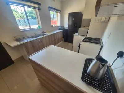 a small kitchen with a counter top and a refrigerator at Ithonsi Guesthouse in Kempton Park