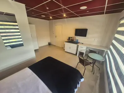 a bedroom with a bed and a desk and a table at Ithonsi Guesthouse in Kempton Park