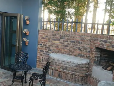 a patio with two chairs and a brick fireplace at Rand Self-catering Accommodation in Carolina