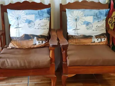 a pair of chairs with pillows with a windmill at Rand Self-catering Accommodation in Carolina