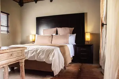 a bedroom with a large bed with a black headboard at Sasavona Game Lodge in Warmbaths