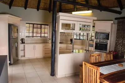 a kitchen with white cabinets and a table and chairs at Sasavona Game Lodge in Warmbaths