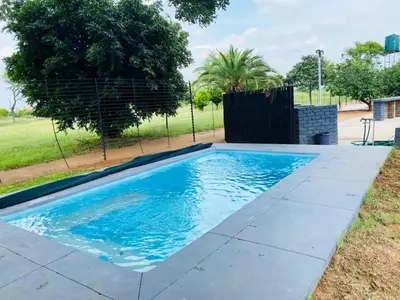 a swimming pool with blue water in a yard at Sasavona Game Lodge in Warmbaths