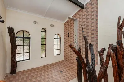 a room with three windows and a brick wall at Airport Tower Lodge in Kempton Park