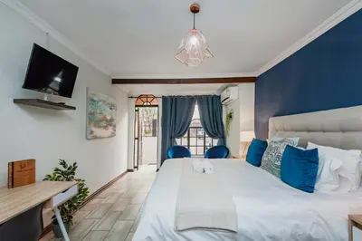 a bedroom with a large bed with blue walls at Airport Tower Lodge in Kempton Park