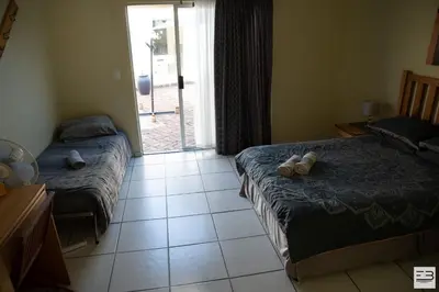 a bedroom with two beds and a door to a yard at Geluksfontein Private Game Farm in Cullinan