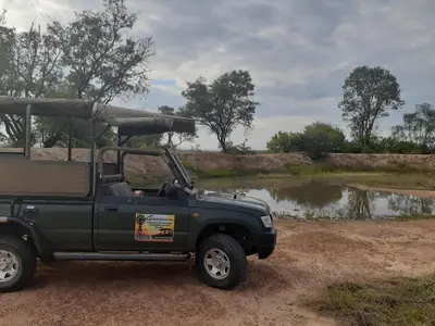 a green jeep parked in front of a river at Geluksfontein Private Game Farm in Cullinan