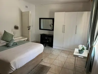 a bedroom with a bed and a table with a mirror at Angelmalatji guesthouse in Graskop