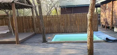 a swimming pool on a wooden deck with a fence at Tranquillity Holiday Home in Marloth Park