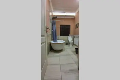a bathroom with two toilets and a tub and a sink at Tranquillity Holiday Home in Marloth Park