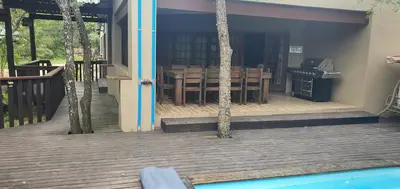a house with a deck with a table and a kitchen at Tranquillity Holiday Home in Marloth Park
