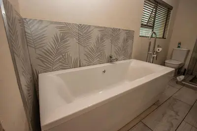 a white bath tub in a bathroom with a toilet at Bushbaby Valley Lodge in Hazyview