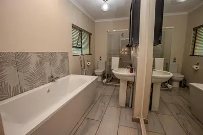 a bathroom with a tub and a sink and a toilet at Bushbaby Valley Lodge in Hazyview