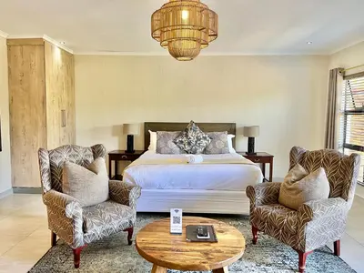 a bedroom with a bed and two chairs and a table at Bushbaby Valley Lodge in Hazyview