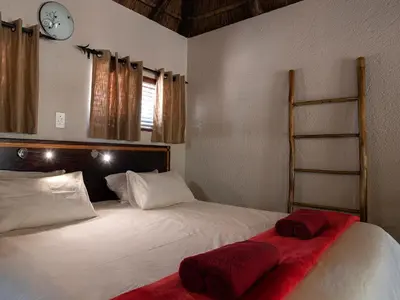 a bedroom with a bed with red sheets and a clock at Mabalingwe Elephant Lodge 267-7 & 267-8 in Mabula