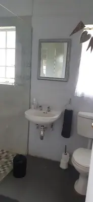 a white bathroom with a toilet and a sink at Die Kothuis in Malelane