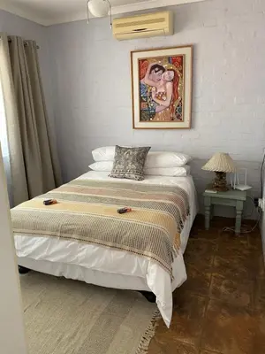 a bedroom with a bed with a painting on the wall at Die Kothuis in Malelane